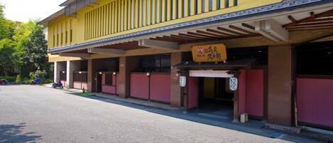 A traditional Japanese building with a yellow facade, a covered entrance, and signage in Japanese.