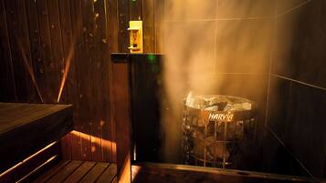 A wooden interior with a bench, a trash bin labeled "HARRIA", and a wall-mounted light fixture.