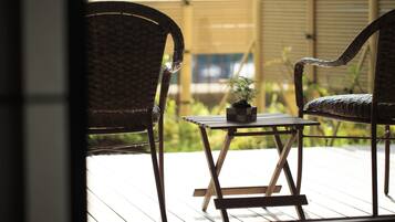 A wicker chair and a small table with a potted plant on a wooden deck.