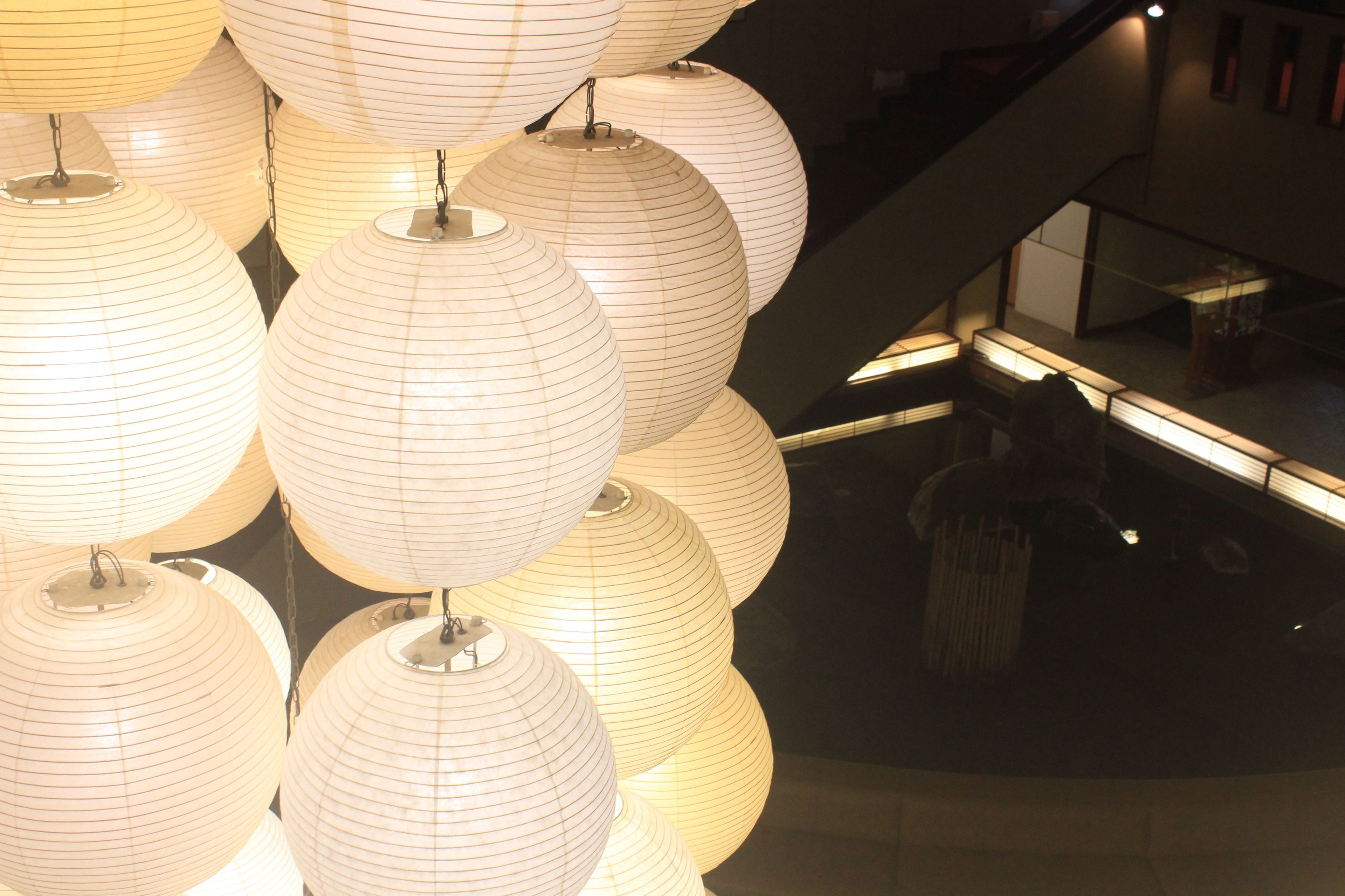 A series of spherical paper lanterns hanging from the ceiling in a well-lit indoor space.