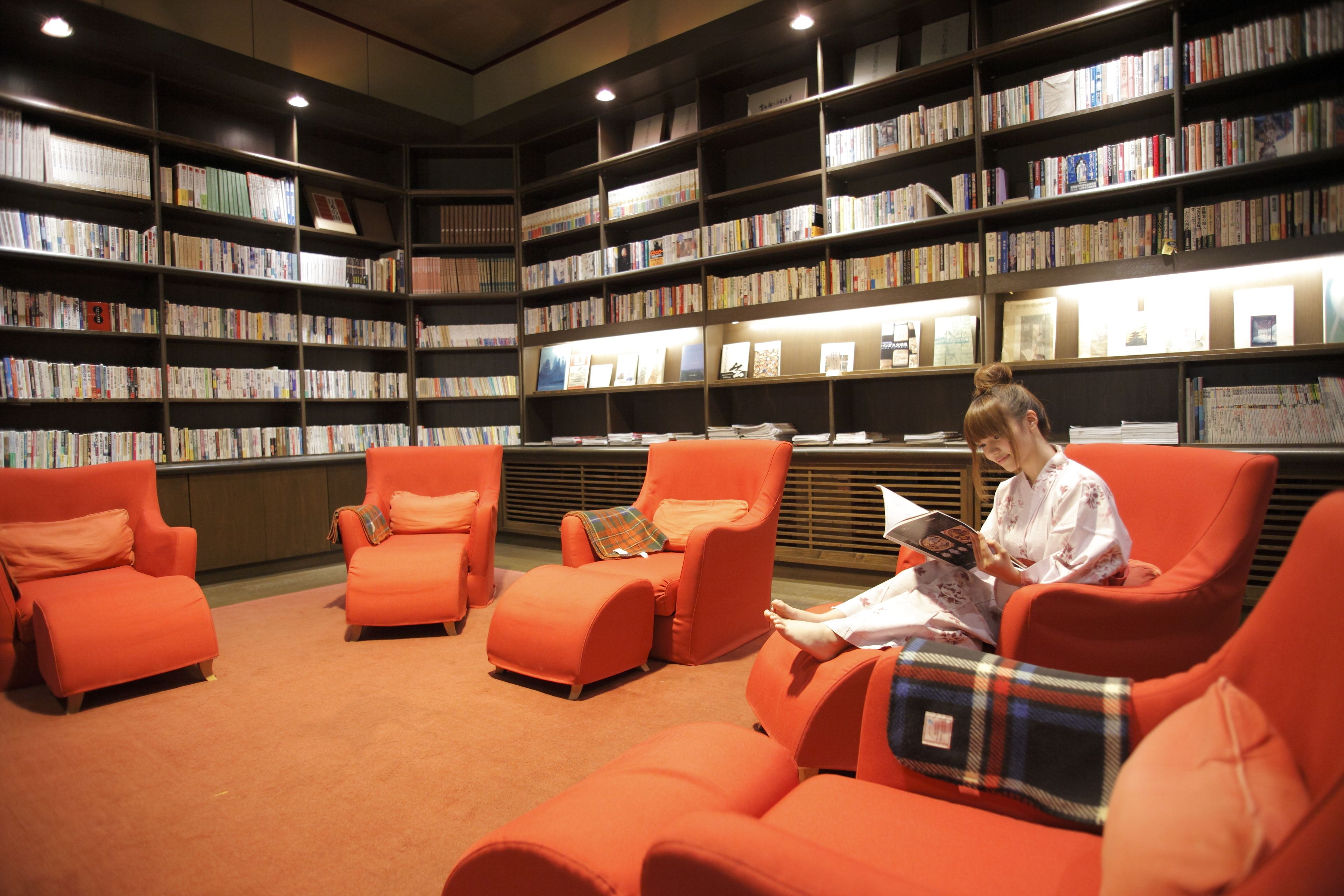 Une bibliothèque avec des étagères et des chaises orange.