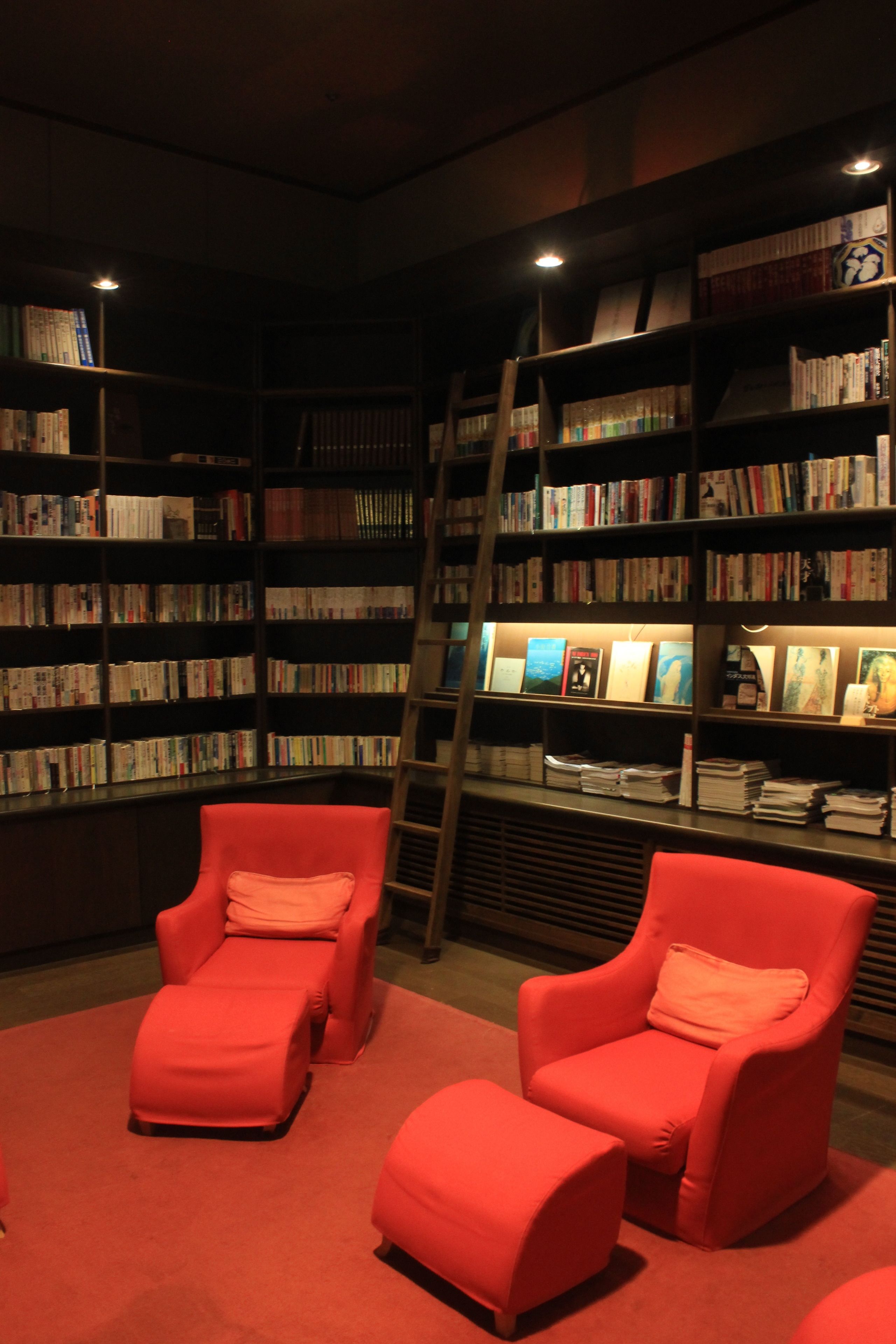 A library with bookshelves, red chairs, and a ladder.