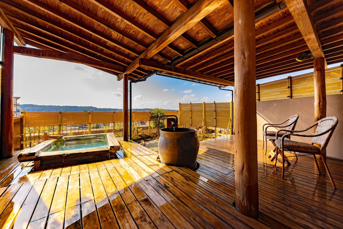 Une terrasse en bois avec un jacuzzi et des chaises, offrant une vue imprenable sur un paysage magnifique.