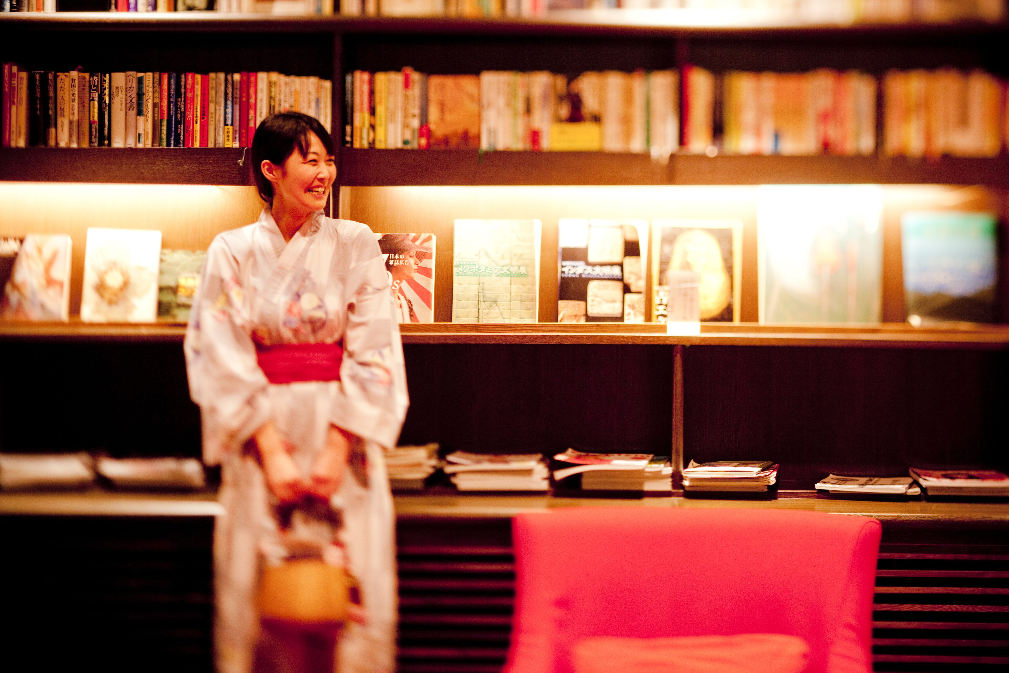 Eine Person in traditioneller Kleidung steht vor einem Bücherregal voller Bücher.