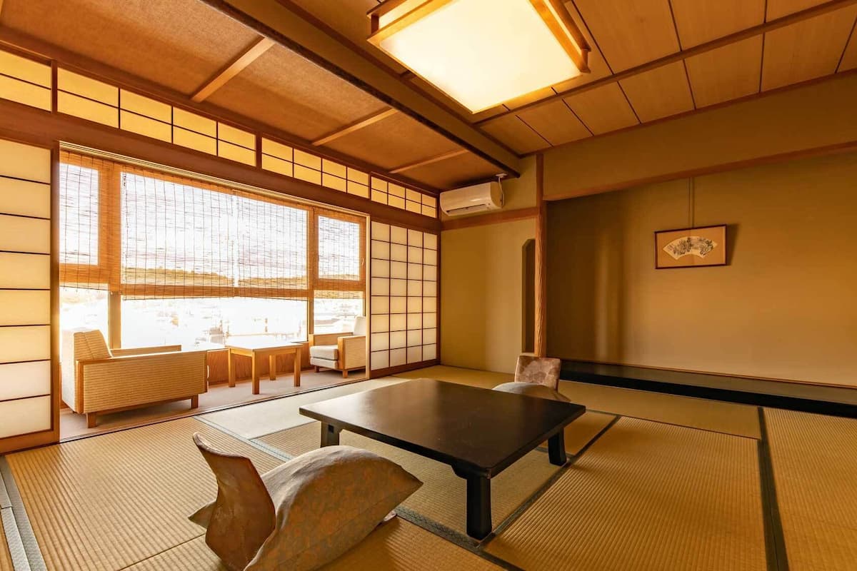Une pièce de style japonais traditionnel, avec un sol recouvert de tatamis, une table basse et des portes coulissantes.