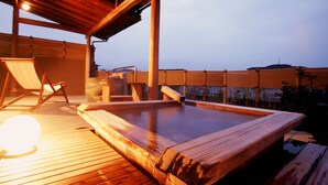 A wooden deck with a hot tub, wooden chairs, and a pergola structure. - Fujiya Ryokan (Kaga)