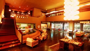 A spacious lobby with a curved seating area, a staircase, and a large chandelier. - Fujiya Ryokan (Kaga)