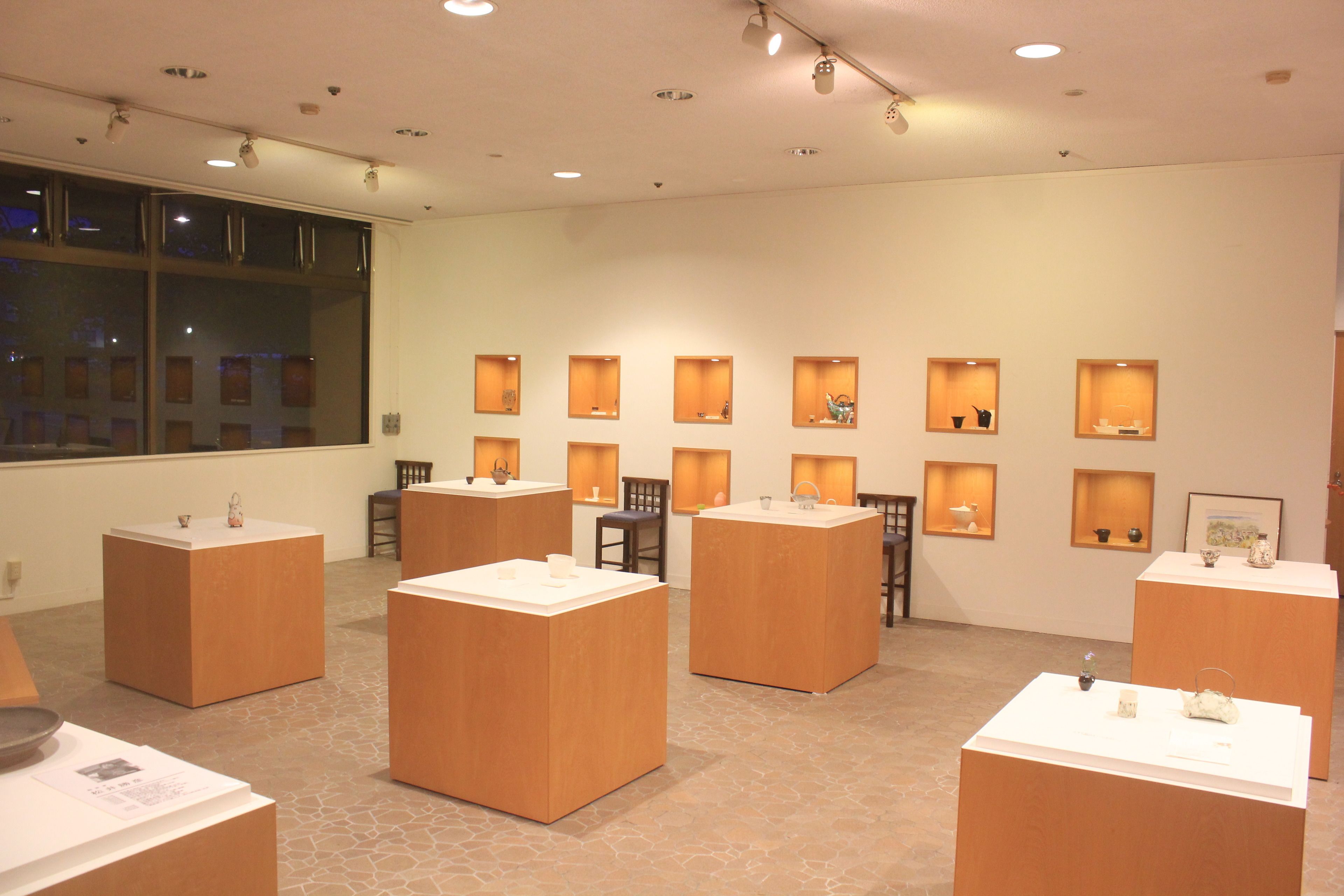 A gallery with wooden display cases and tables, featuring various items on display.