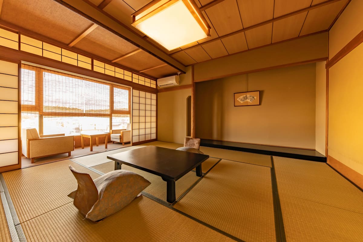 Une pièce de style japonais traditionnel, avec un sol recouvert de tatamis, une table basse, des coussins et des portes coulissantes.