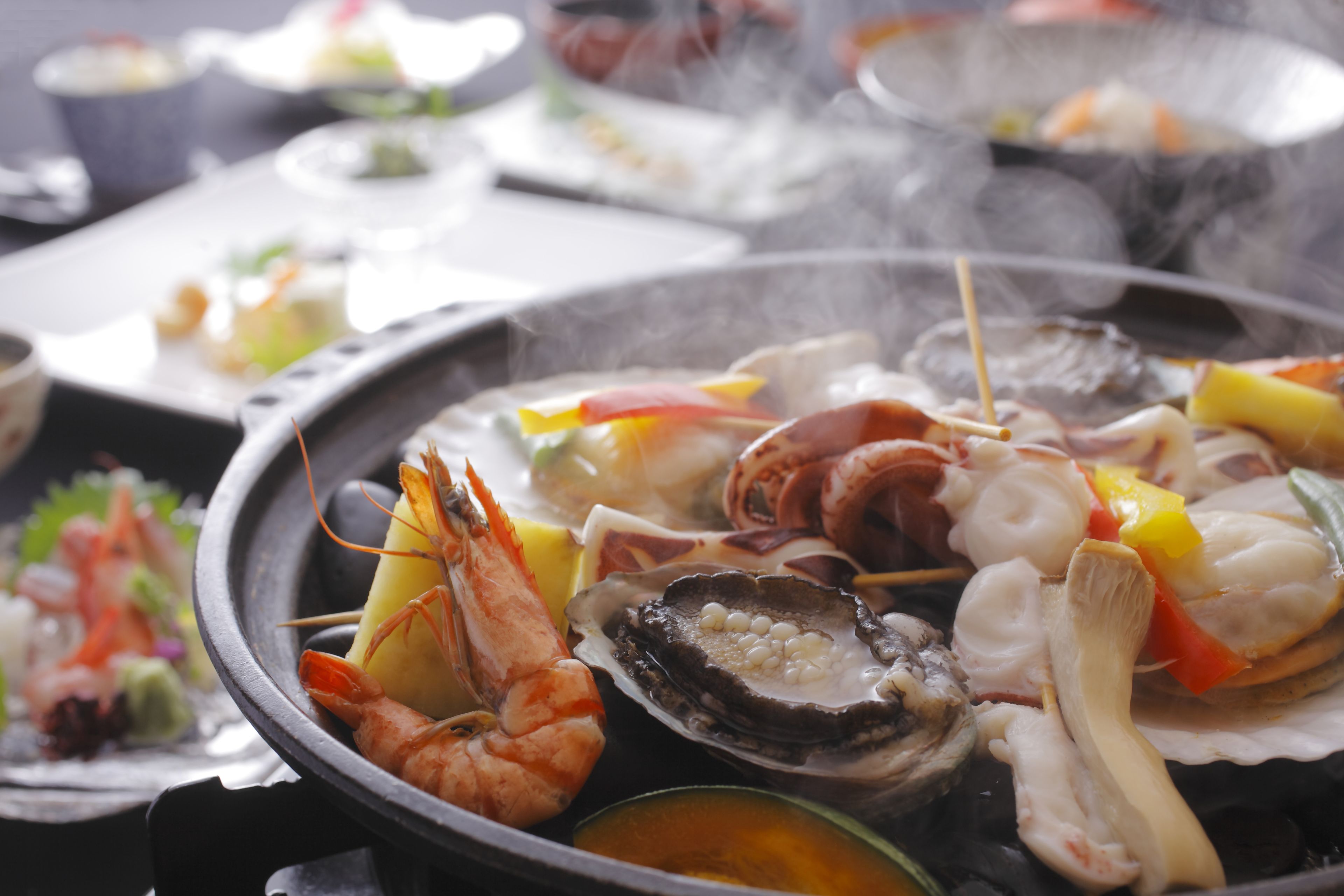 A seafood grill with various types of seafood, including shrimp, oysters, and squid, with a steaming effect.