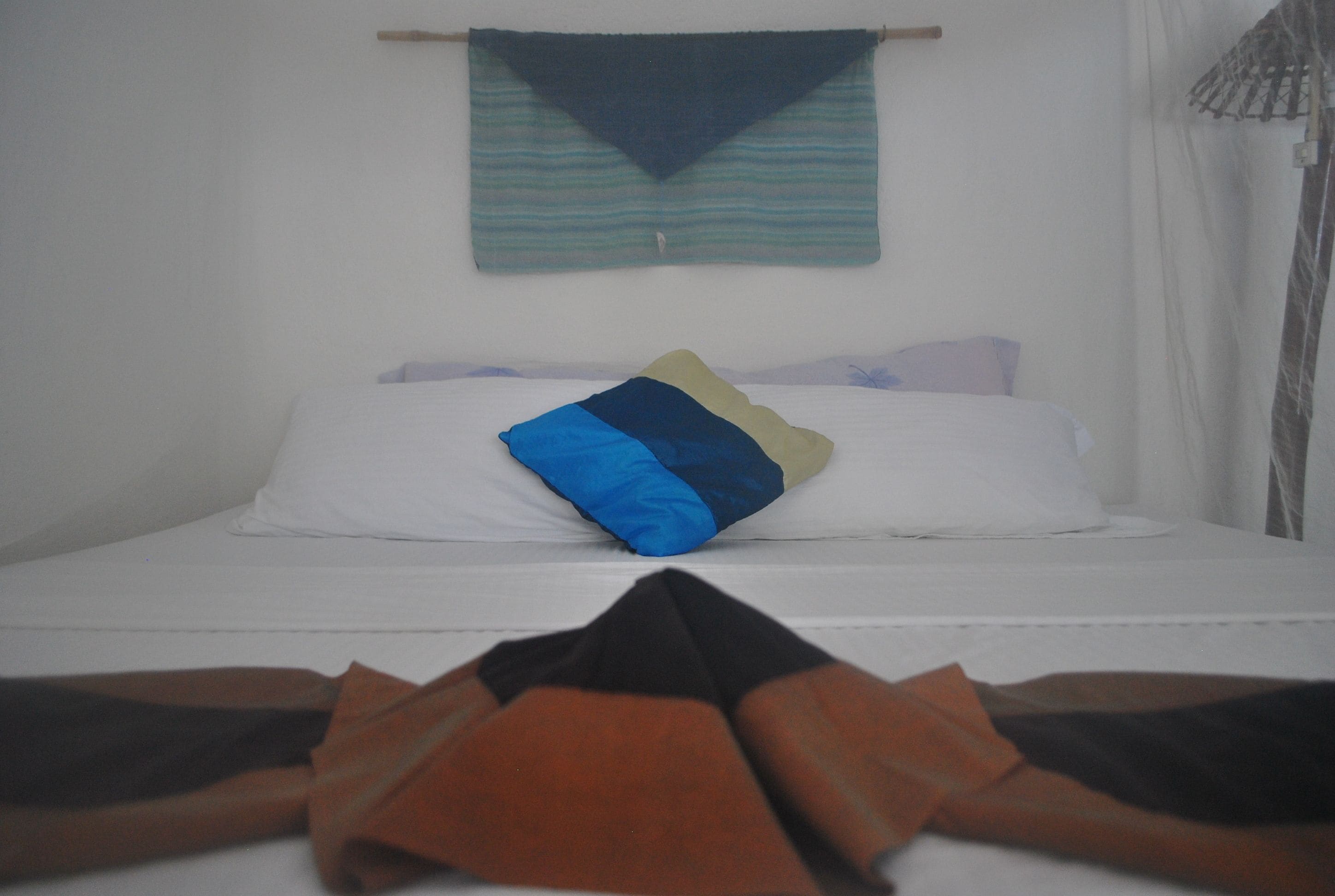 A bed with a white mattress, a blue and beige pillow, and a dark blue blanket.