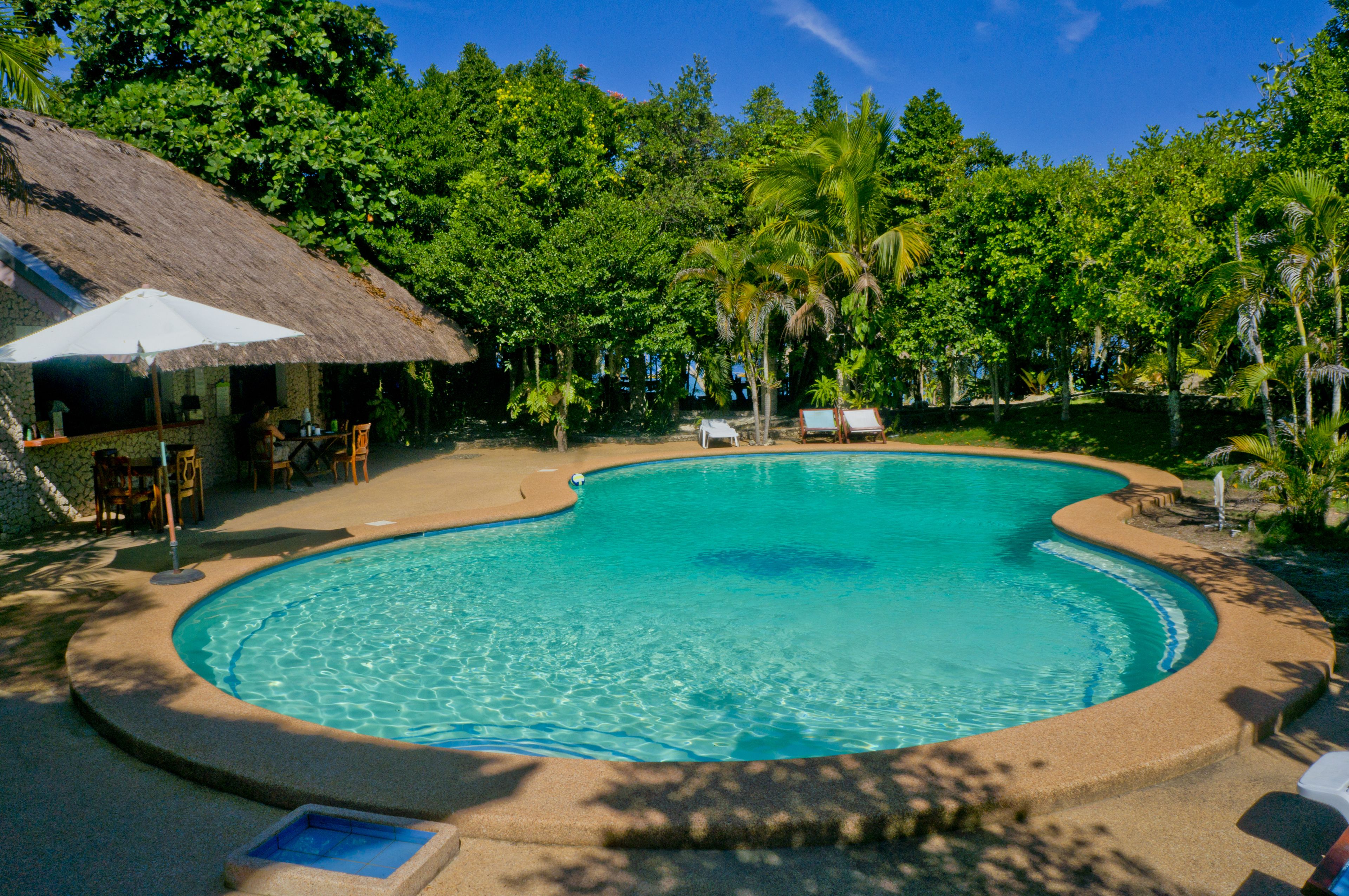 Una piscina al aire libre, sillones reclinables de piscina