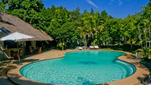 A swimming pool with lounge chairs and a thatched-roof structure. - The Blue Orchid Resort (Moalboal)