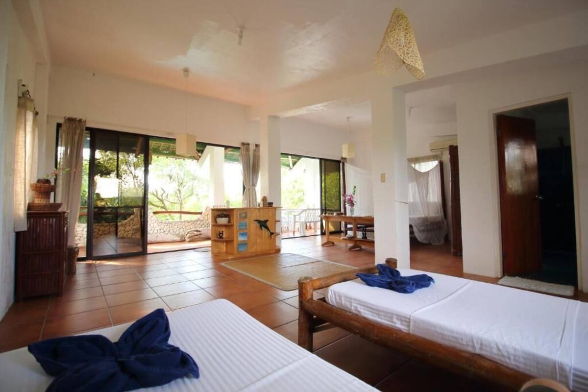A room with two beds, a wooden desk, and a view of the outdoors.