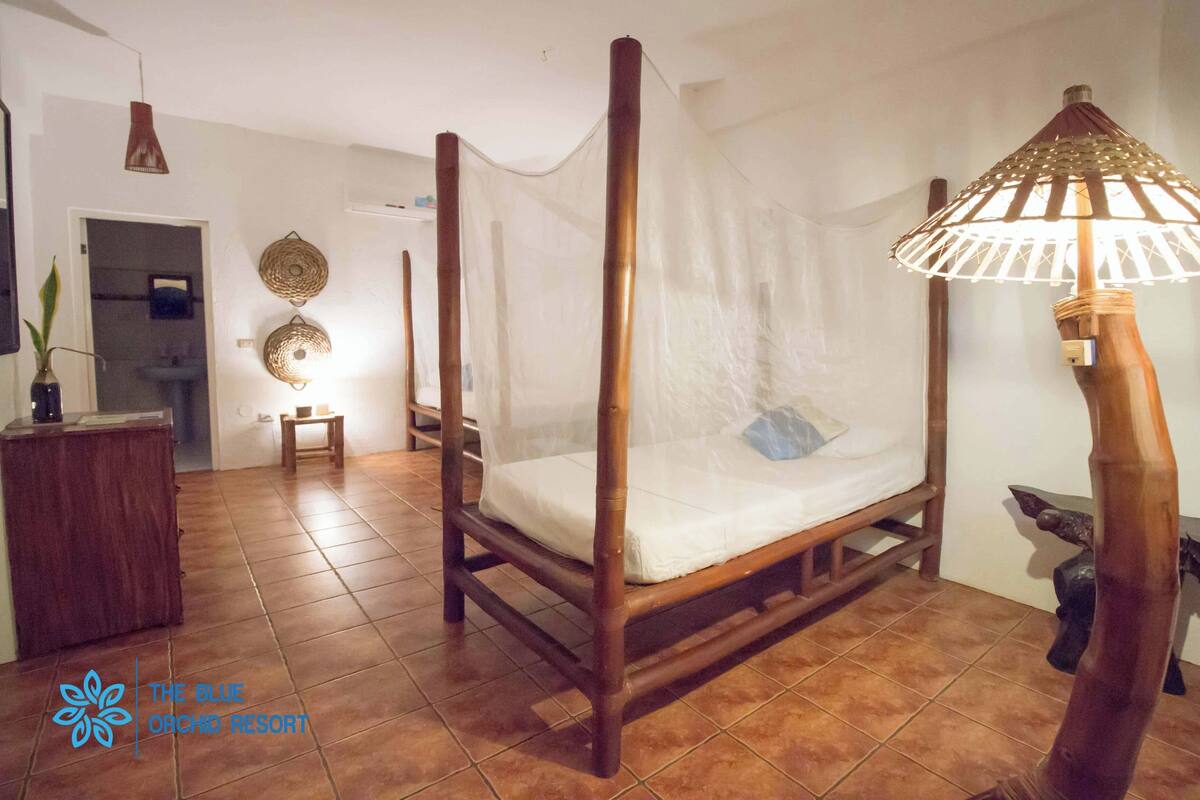 A room with a four-poster bed, a wooden nightstand, a small table, and a decorative lamp.