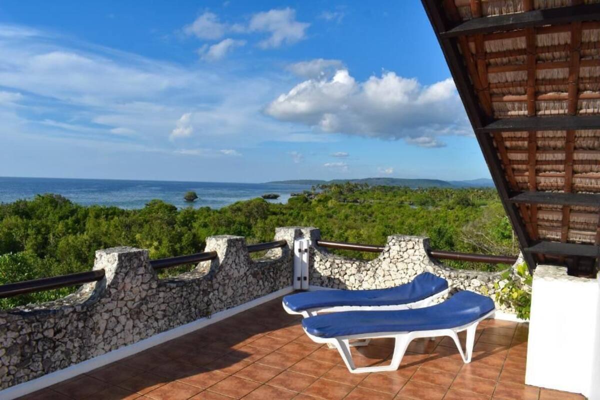 A balcony with two sun loungers overlooking a coastal view.