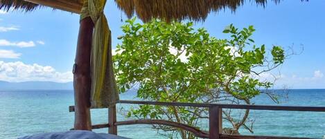 A bed with a view of the ocean and a tree.