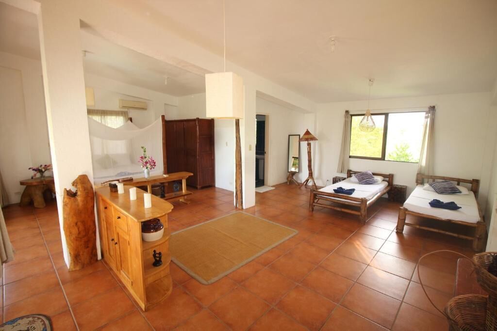 A spacious room with a wooden bench, a small table, and a bed with a canopy.