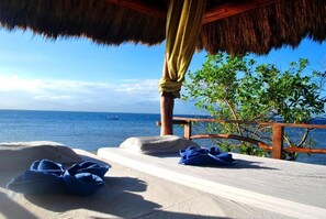 A beachside room with a thatched roof, a wooden railing, and a view of the sea. - The Blue Orchid Resort (Moalboal)