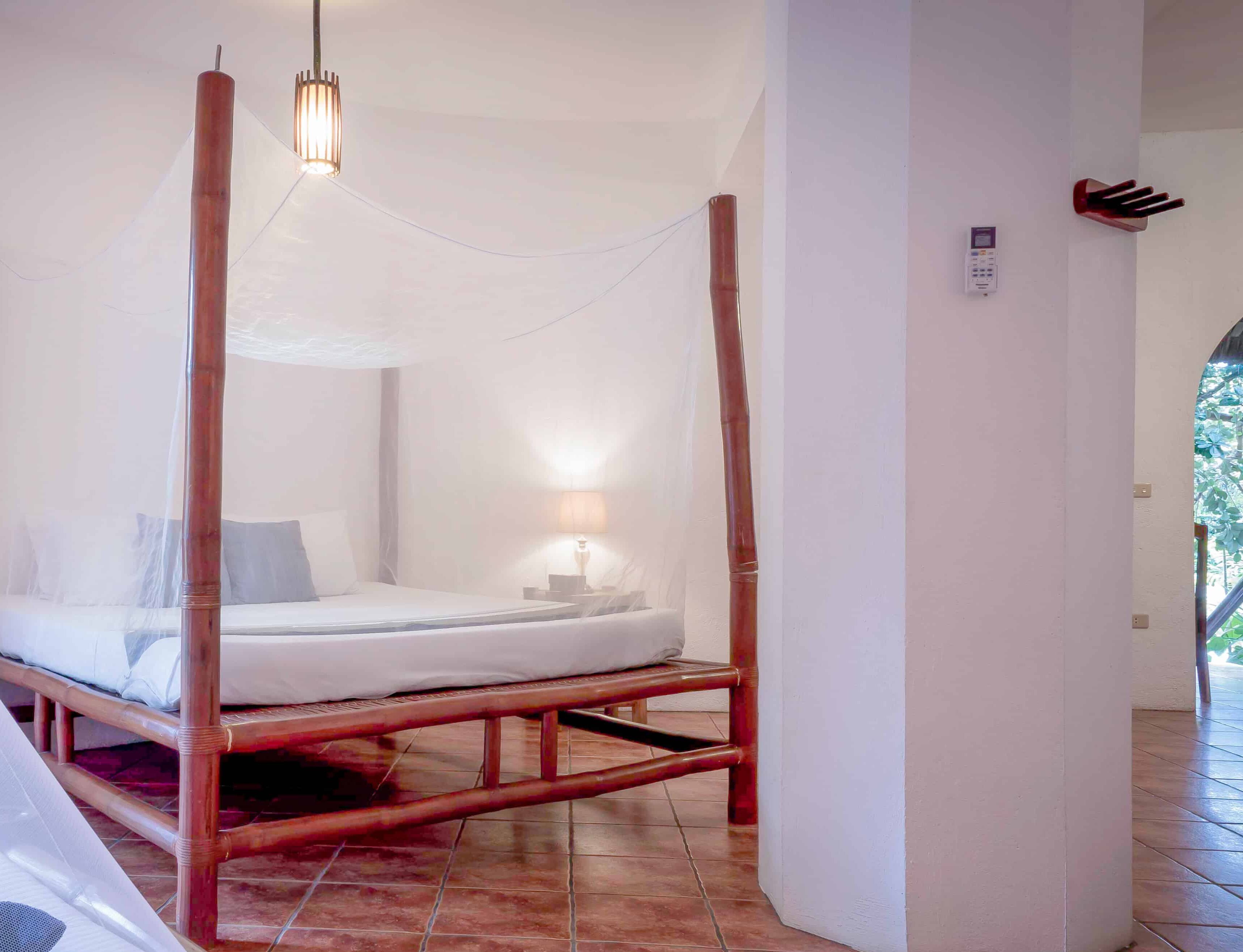Ein Zimmer mit einem Himmelbett, einer Nachttischlampe und einem an der Wand montierten Thermostat.