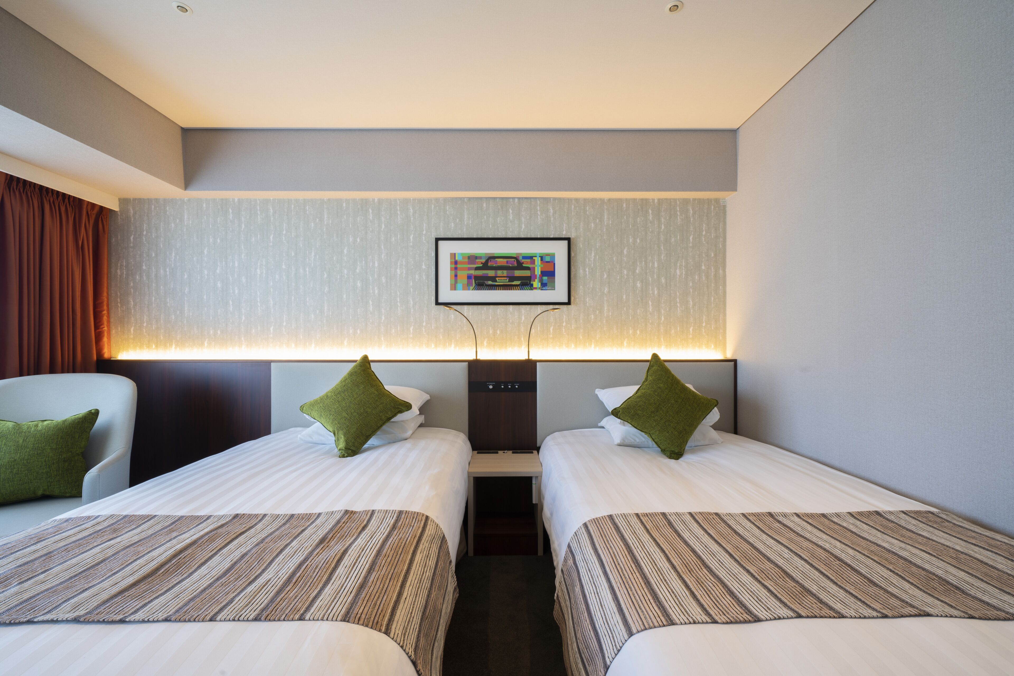 Habitación de hotel con dos camas, un escritorio, una silla y un cuadro en la pared.