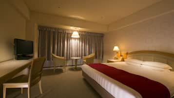Ein Hotelzimmer mit Bett, Schreibtisch, Stuhl, Fernseher und Lampe.
