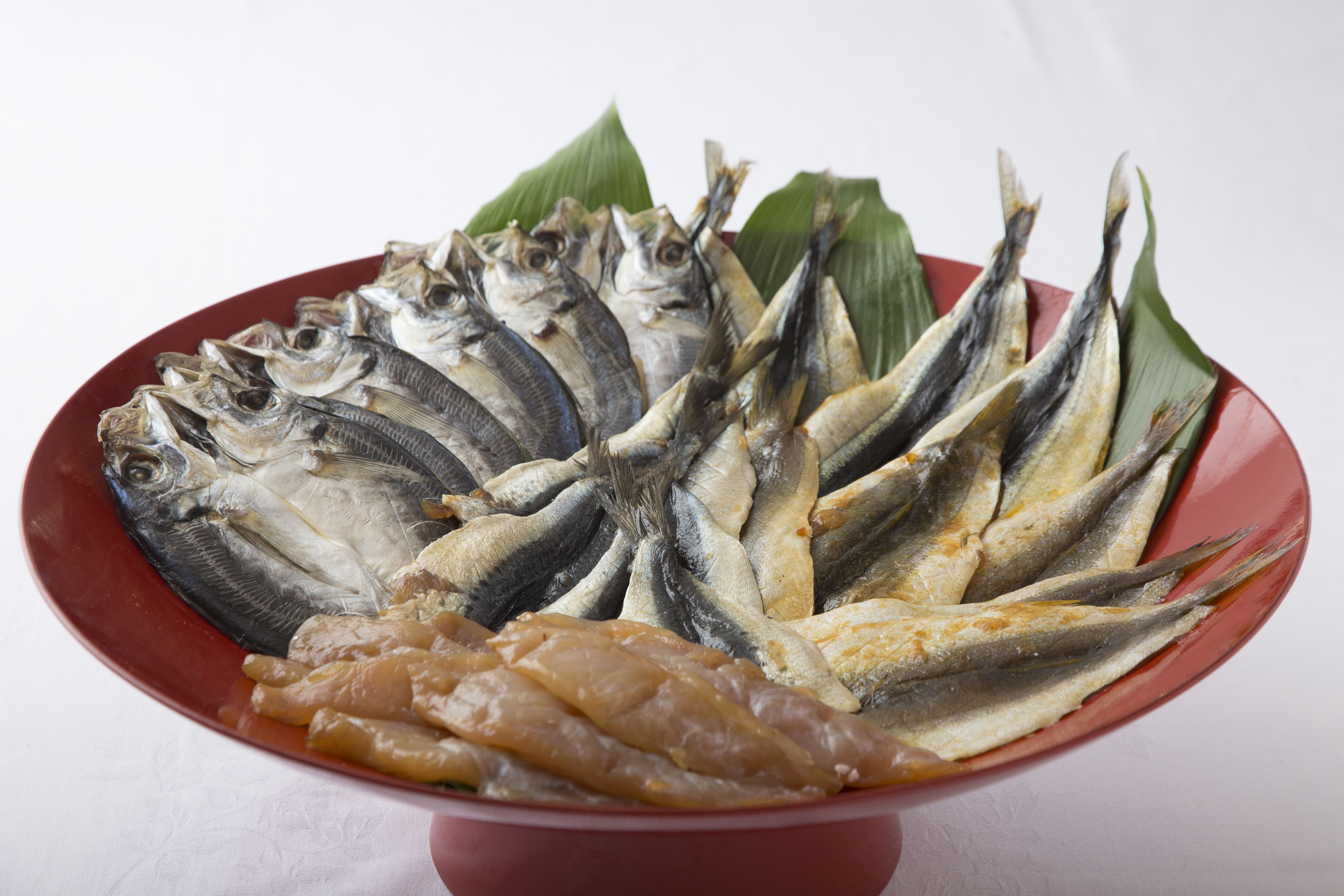 A plate of dried fish and a bowl of chicken.