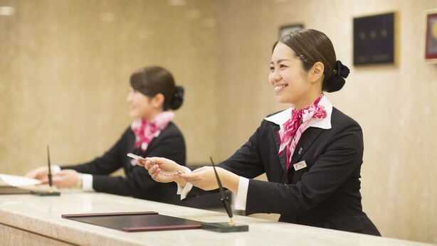 A reception desk with two staff members. - Meitetsu Toyota Hotel (Toyota)