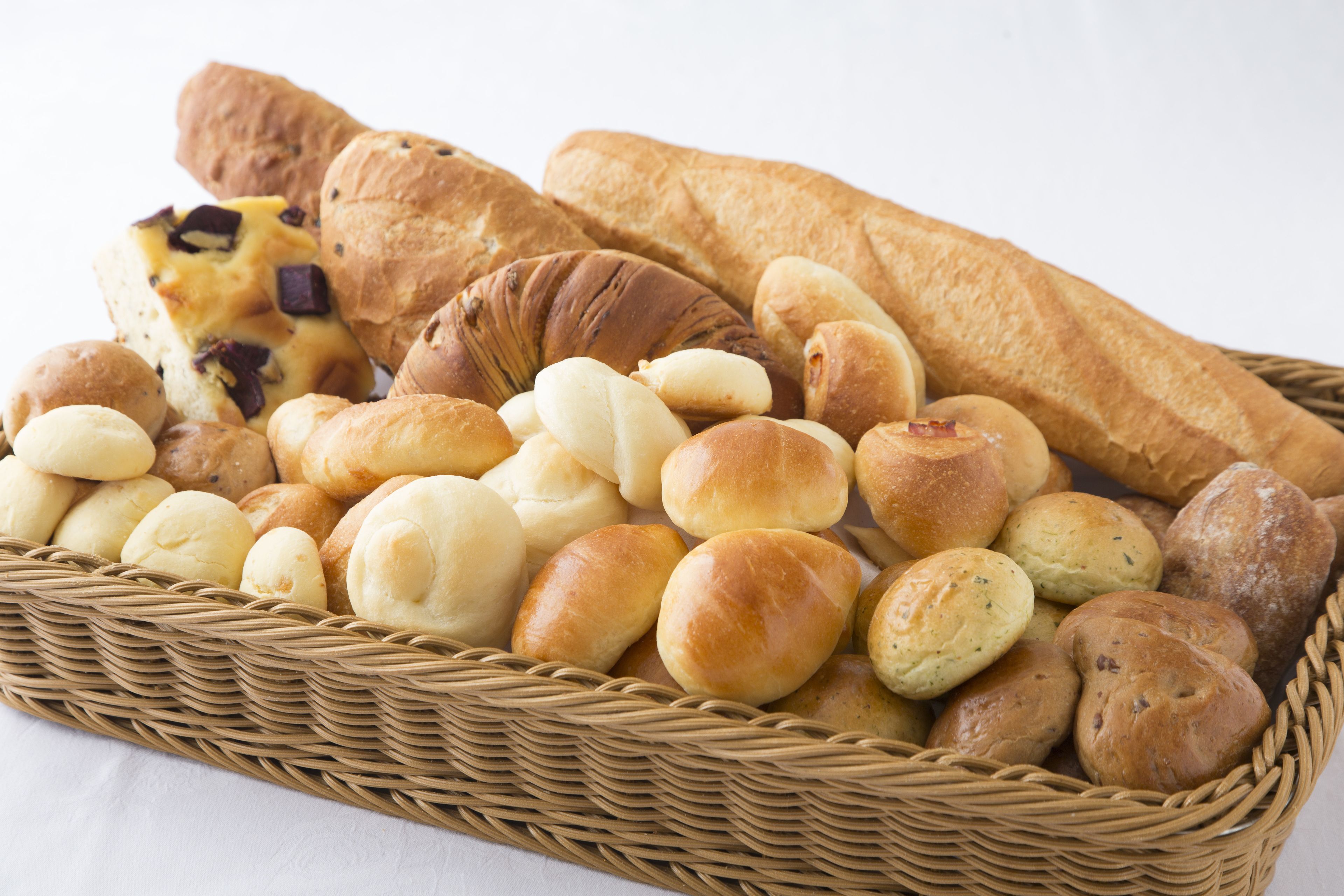 Una cesta con panes y pasteles varios.