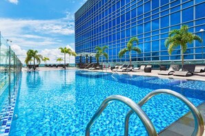 A modern hotel pool area with clear blue water, lounge chairs, and palm trees. - Richmonde Hotel Iloilo (Iloilo)