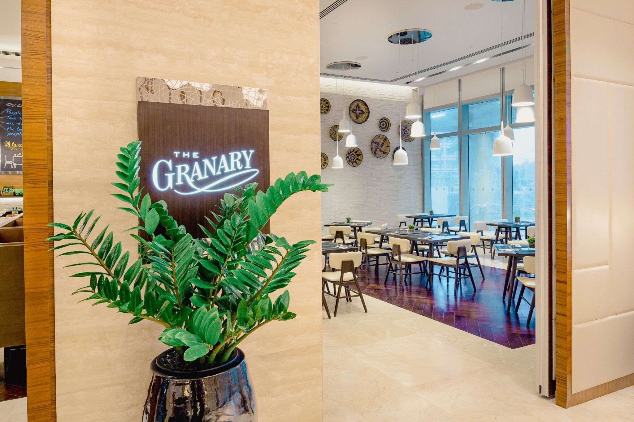 A modern dining area with a sign reading "The Granary" and a potted plant in the foreground.