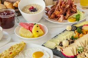 A breakfast spread with various foods including eggs, bacon, fruits, and cheese. - Richmonde Hotel Iloilo (Iloilo)