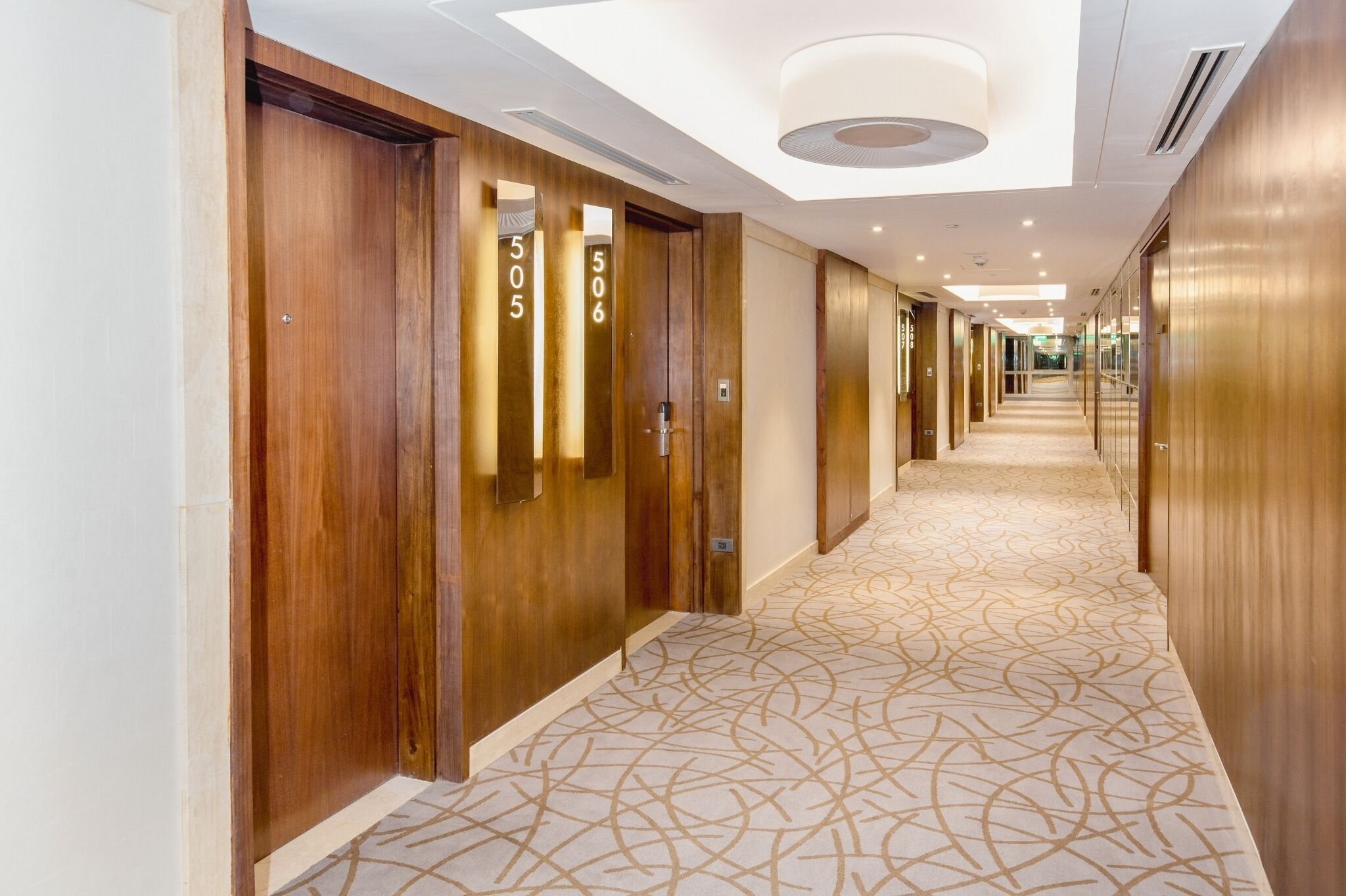 A hotel corridor with wooden doors, numbered 505 and 506, and a patterned carpet.