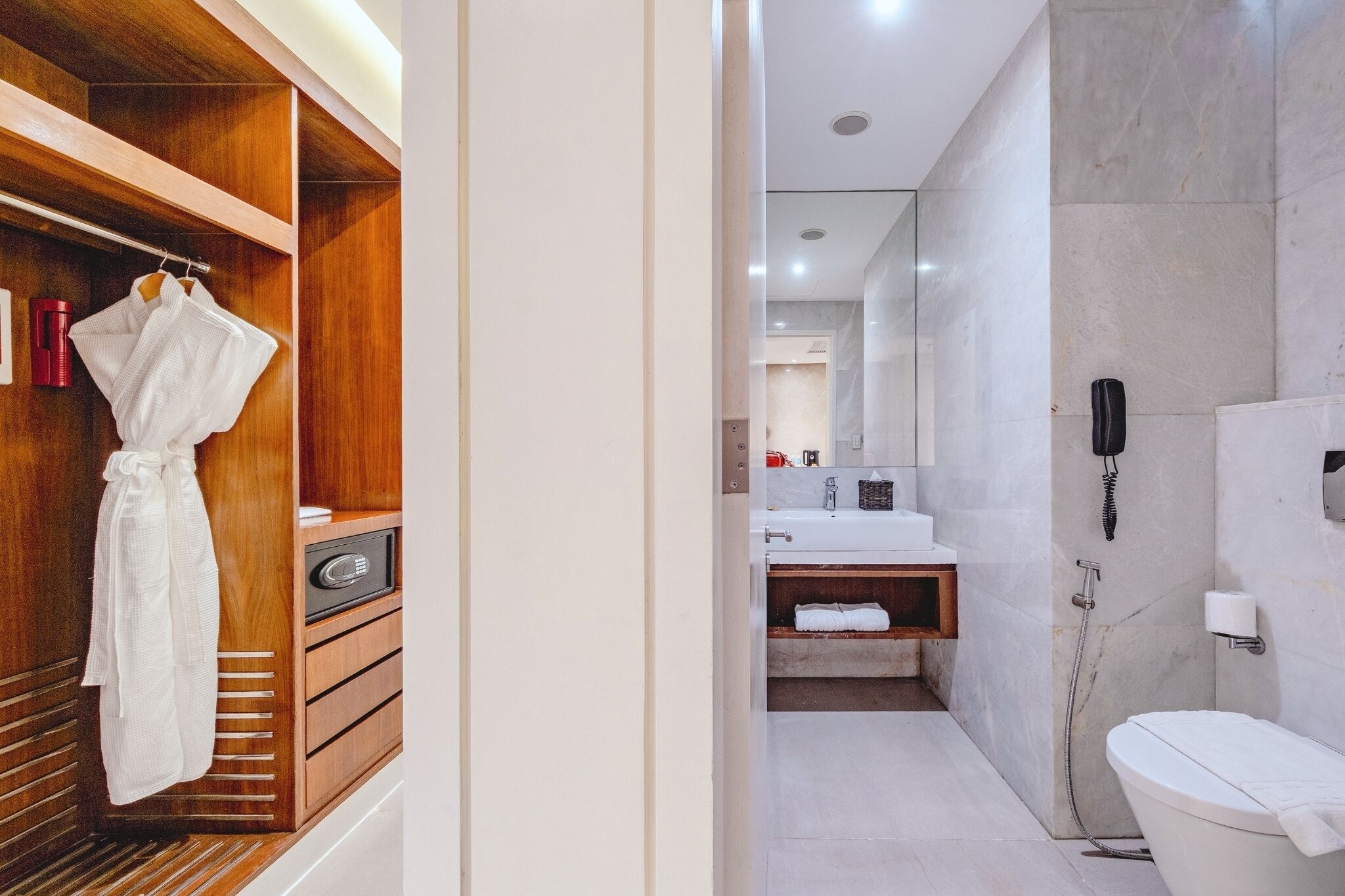 Un baño moderno con tocador de madera, inodoro blanco y zona de ducha.