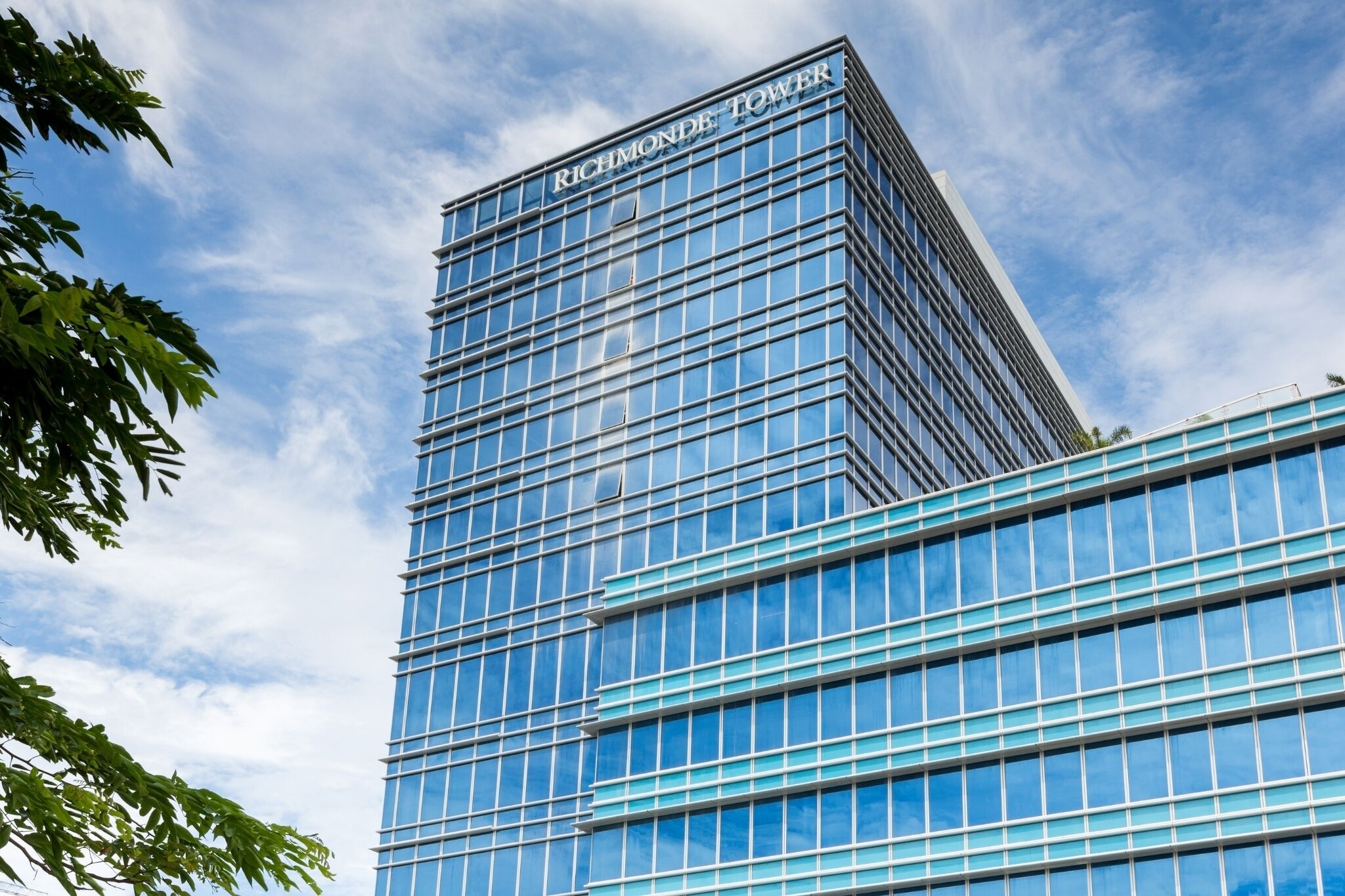 Ein hohes, modernes Glasgebäude mit dem Namen "Richmond Tower" auf der Spitze.