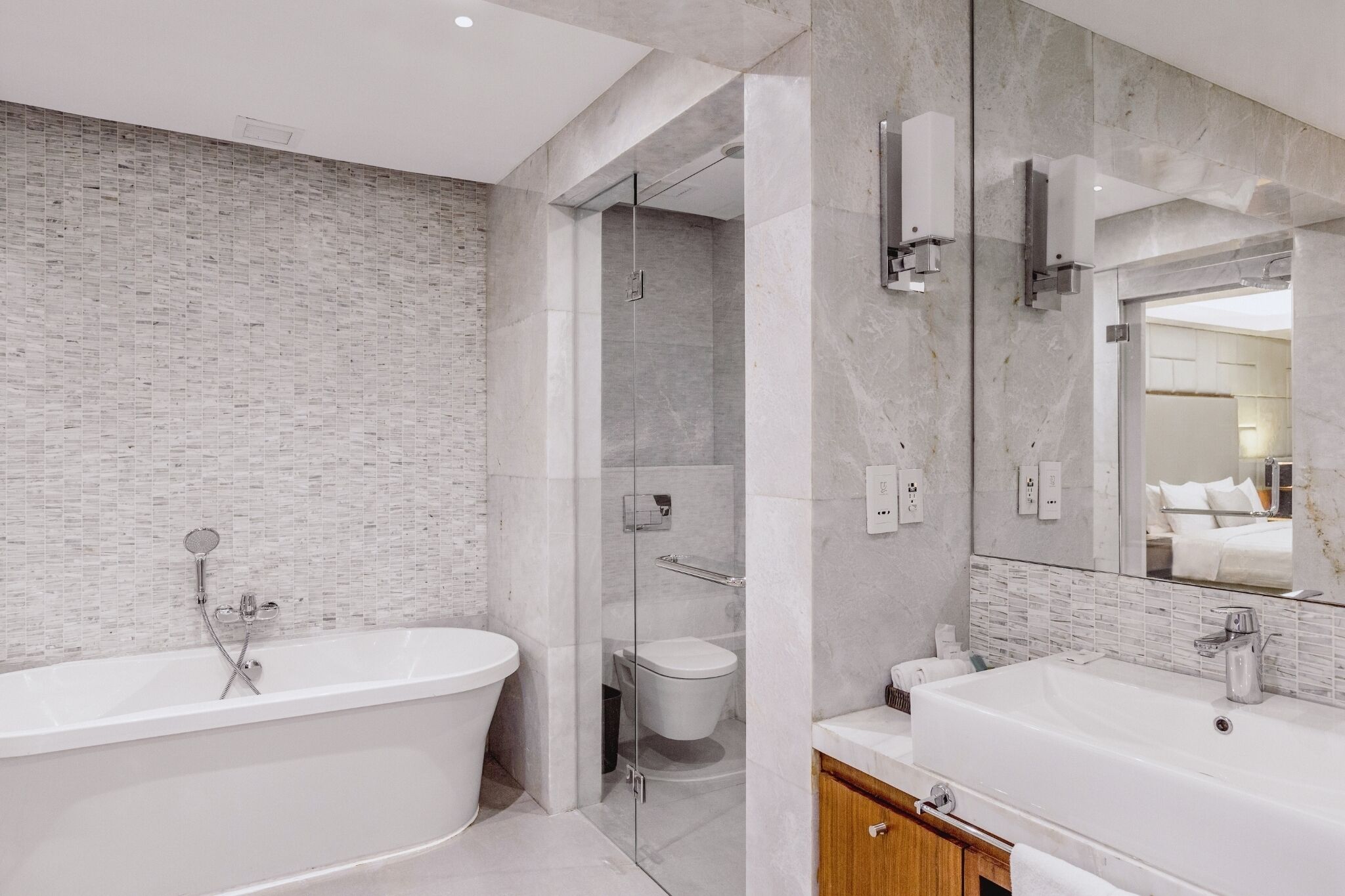 Un baño moderno con una bañera independiente, una ducha con cerramiento de vidrio y un espejo grande sobre el lavamanos.