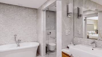 Un baño moderno con una bañera independiente, una ducha con cerramiento de vidrio y un espejo grande sobre el lavamanos.