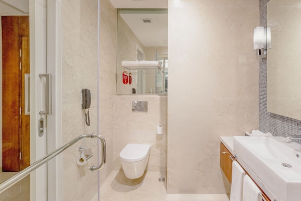 Un baño moderno con cabina de ducha de vidrio, un inodoro blanco y un lavabo con espejo.