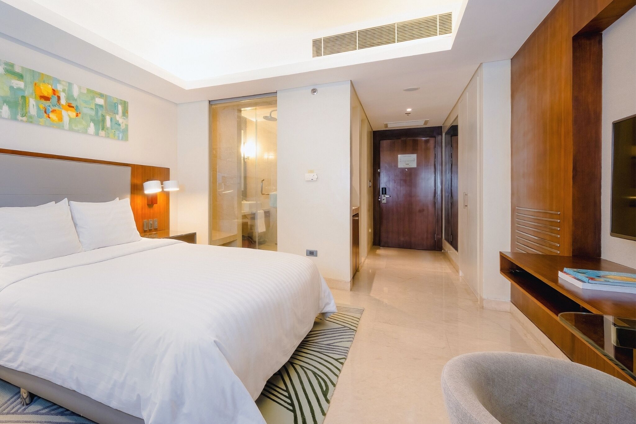 A modern hotel room with a large bed, a desk, and a television.
