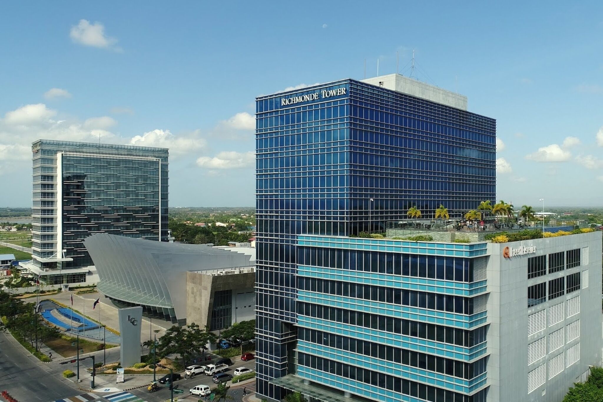 A modern building complex with a prominent glass facade and a rooftop garden.