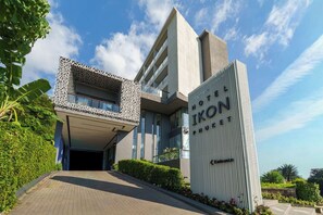 A modern hotel with a distinctive facade, including a patterned section and a tall vertical sign. - Hotel IKON Phuket (Karon)
