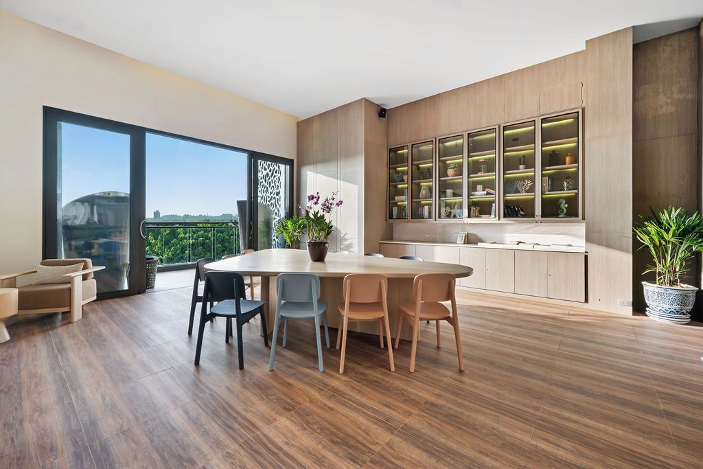 Une cuisine moderne dotée d’un grand îlot central, de meubles de rangement intégrés et offrant une vue sur la verdure.