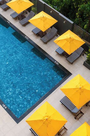 A swimming pool with lounge chairs and yellow umbrellas. - Hotel IKON Phuket (Karon)