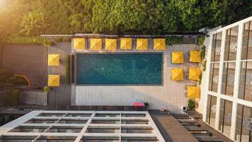 A rooftop pool with multiple yellow umbrellas, a glass building to the right, and a staircase leading down.