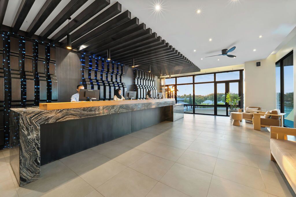 A modern reception area with a marble counter, a ceiling fan, and large windows offering a view of the outdoors.