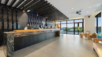 A modern reception area with a marble counter, a ceiling fan, and large windows offering a view of the outdoors.