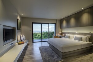 A modern bedroom with a large bed, a flat-screen TV, and a balcony with a city view.