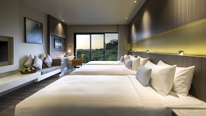 A modern hotel room with two large beds, a desk, and a view of the outdoors.