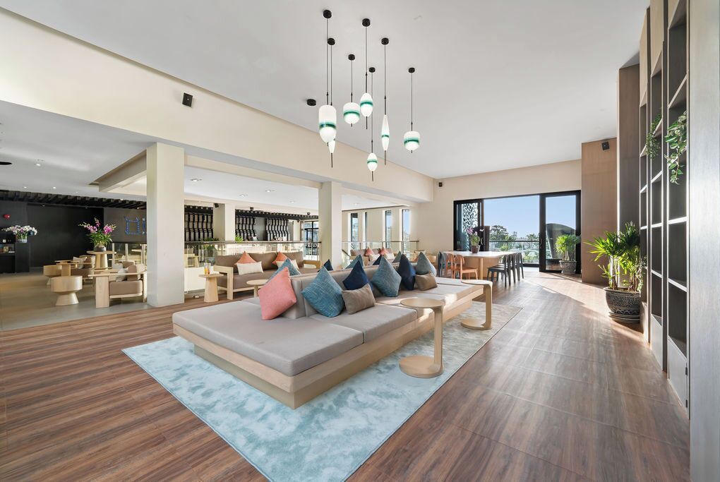 A spacious hotel lobby with a large seating area, a bar, and a view of the city.