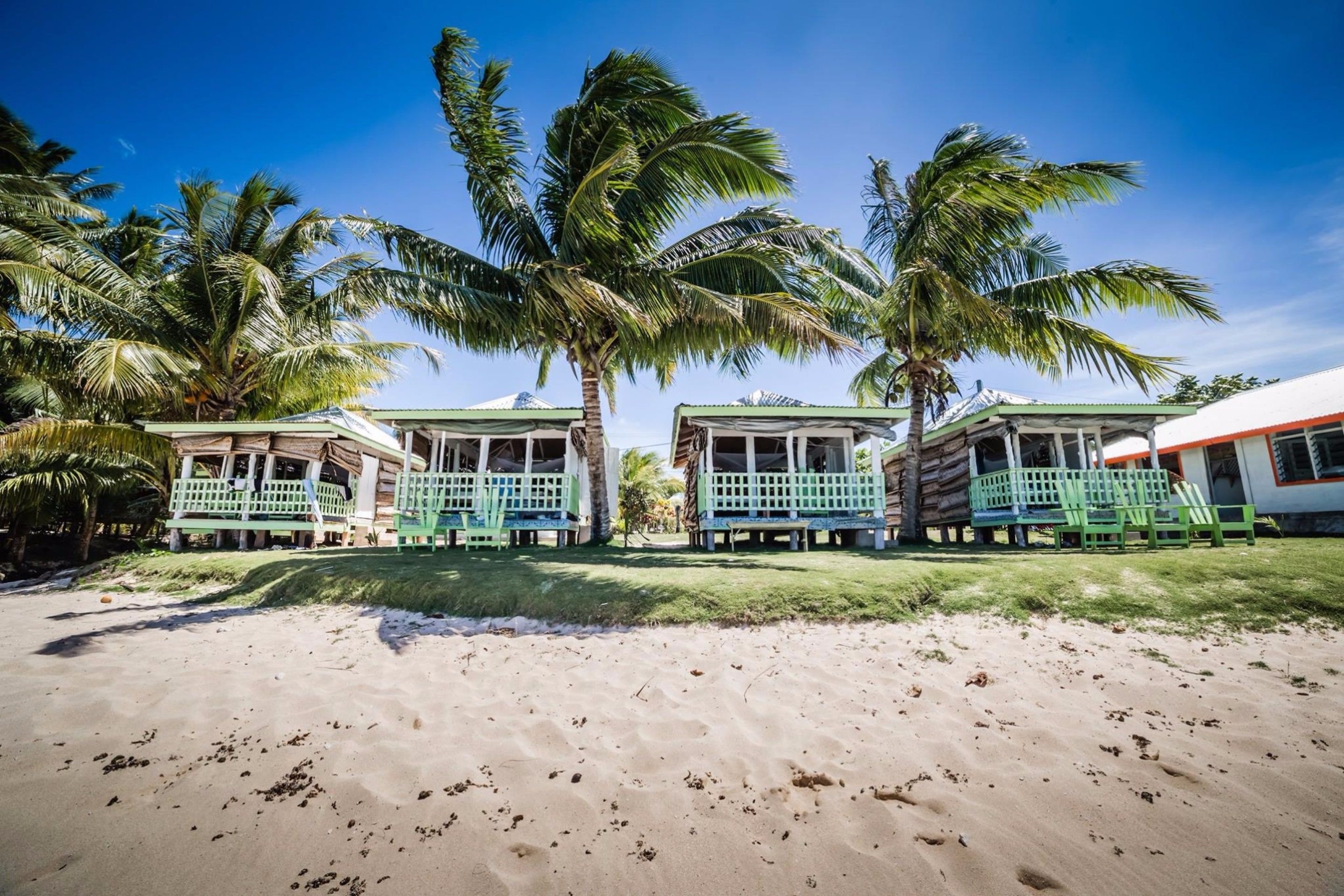 A beachside resort with three bungalow-style buildings, each with a porch and seating area.